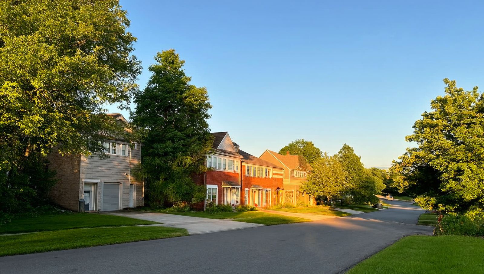 A quiet Brampton residential street with detached two-story homes bathed in golden-hour light